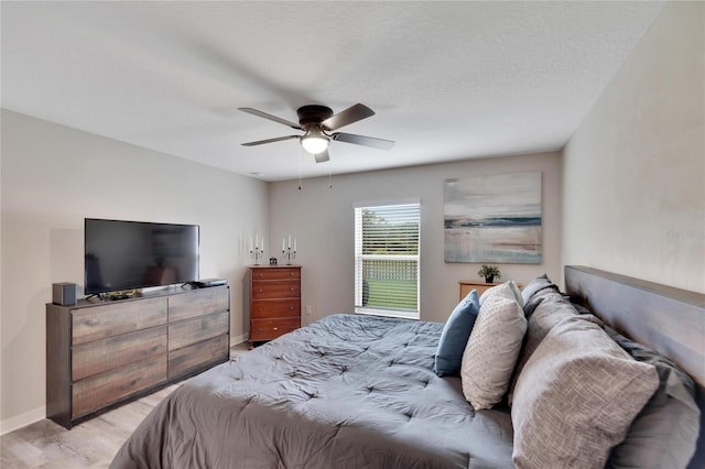 bedroom featuring ceiling fan, a textured ceiling, and light hardwood / wood-style floors