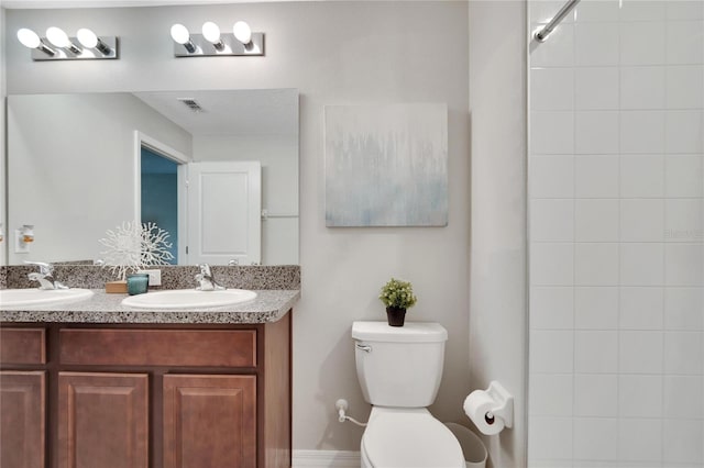 bathroom with vanity, tiled shower, and toilet