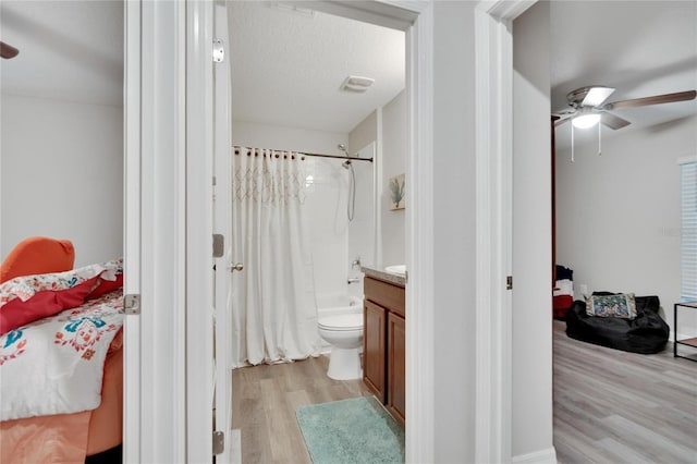 full bathroom with ceiling fan, wood-type flooring, shower / bath combo with shower curtain, toilet, and vanity