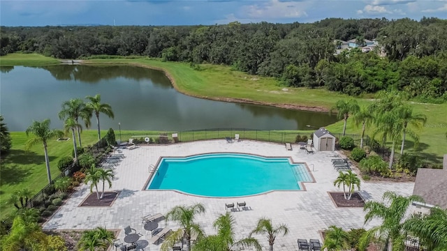 view of pool with a patio, a storage shed, a water view, and a yard