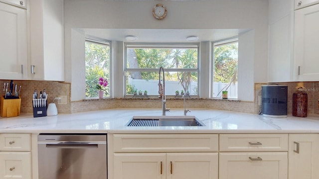 411 Harbor View Ln, Largo, FL 33770 - kitchen with stainless steel dishwasher, a sink, backsplash, white cabinetry, and light stone countertops