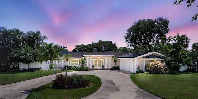 411 Harbor View Ln, Largo, FL 33770 - view of front of home featuring french doors, a yard, concrete driveway, stucco siding, and an attached garage