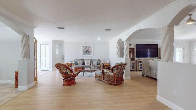 411 Harbor View Ln, Largo, FL 33770 - living room featuring arched walkways, light wood finished floors, crown molding, a ceiling fan, and baseboards