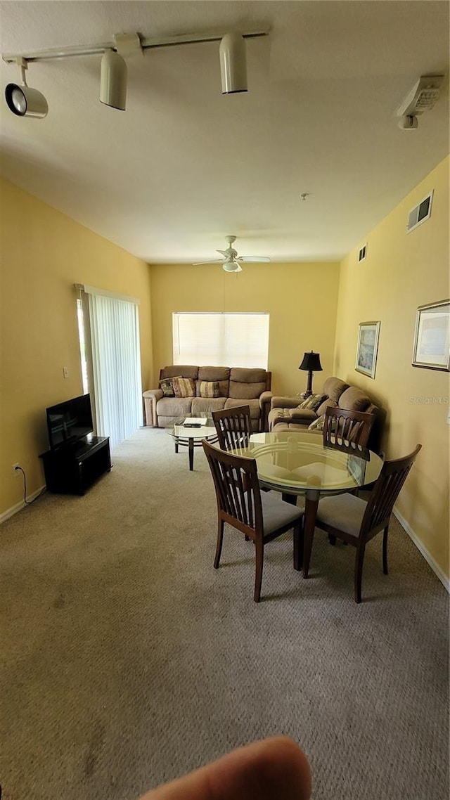 carpeted dining room with ceiling fan