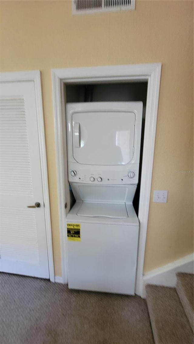 laundry room with stacked washer / dryer and carpet floors