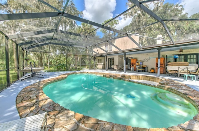 view of swimming pool with a patio, ceiling fan, and glass enclosure