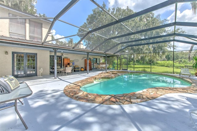 view of swimming pool featuring a patio, glass enclosure, and french doors