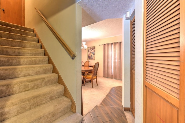 staircase featuring a textured ceiling and carpet