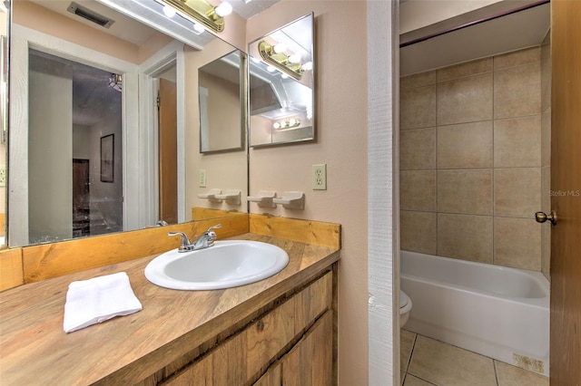 full bathroom featuring tiled shower / bath, vanity, toilet, and tile patterned floors