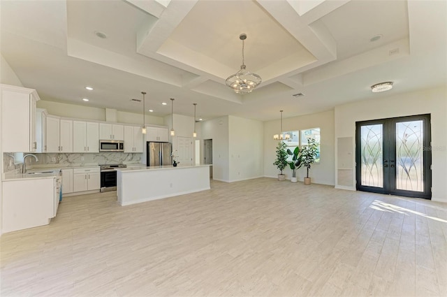 kitchen with white cabinets, a kitchen island, decorative light fixtures, appliances with stainless steel finishes, and an inviting chandelier