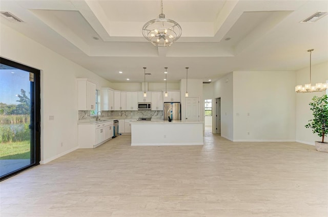 kitchen featuring stainless steel appliances, white cabinets, a center island, and decorative light fixtures