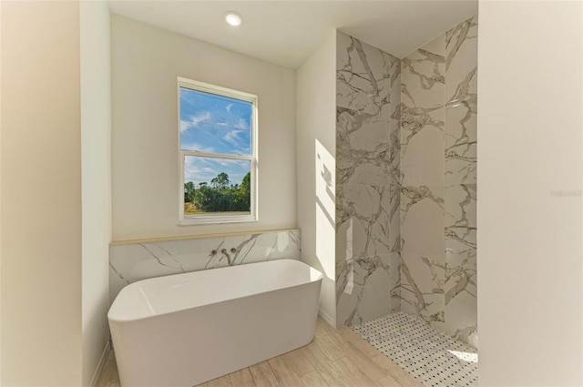 bathroom featuring plus walk in shower, tile walls, and hardwood / wood-style flooring