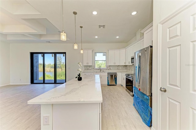 kitchen featuring appliances with stainless steel finishes, plenty of natural light, white cabinetry, and a center island