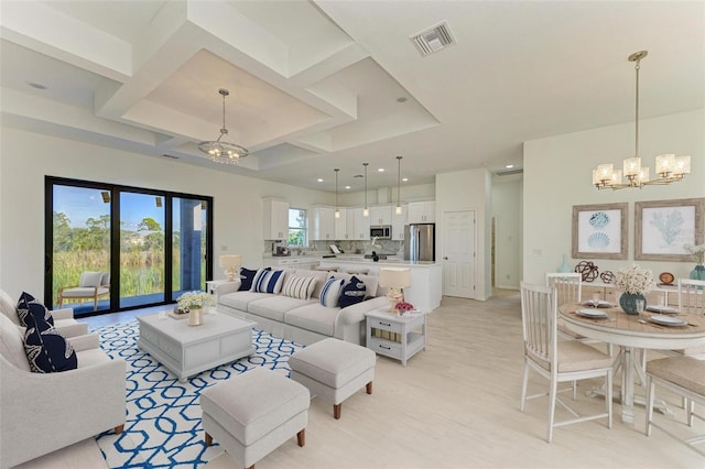 living room with light hardwood / wood-style floors, coffered ceiling, and a chandelier