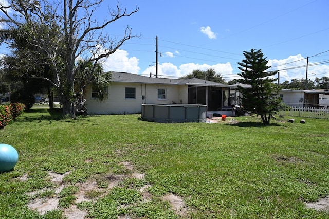 view of yard featuring an outdoor pool, fence, and a sunroom