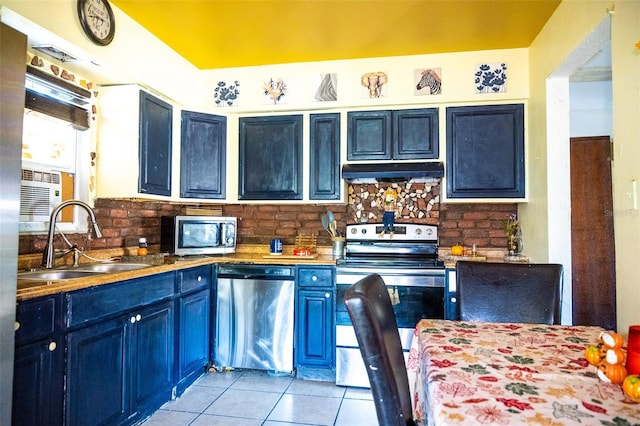 kitchen featuring appliances with stainless steel finishes, tasteful backsplash, blue cabinets, sink, and light tile patterned floors