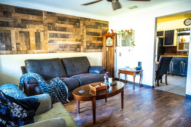 living room featuring hardwood / wood-style flooring, ceiling fan, and wood walls