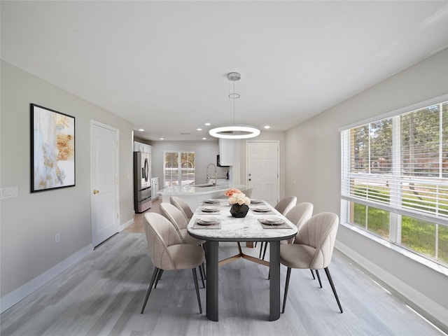 dining space featuring sink, light hardwood / wood-style floors, and a healthy amount of sunlight