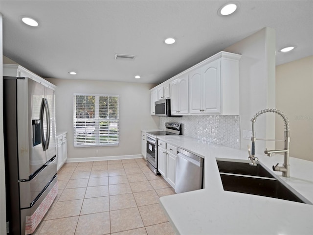 kitchen with light tile patterned flooring, appliances with stainless steel finishes, white cabinetry, and sink