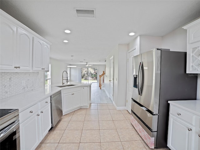 kitchen featuring light tile patterned floors, stainless steel appliances, white cabinetry, sink, and kitchen peninsula