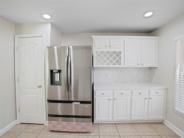 kitchen with light tile patterned floors, stainless steel fridge, decorative backsplash, and white cabinets