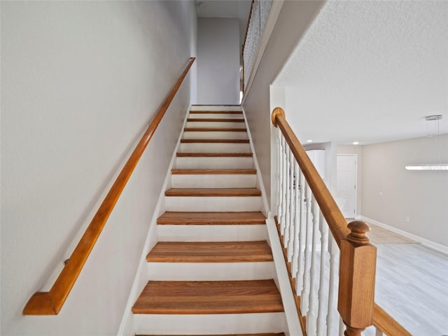 stairway with wood-type flooring and a textured ceiling