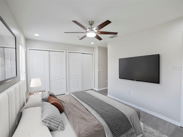 bedroom with dark wood-type flooring, ceiling fan, and multiple closets