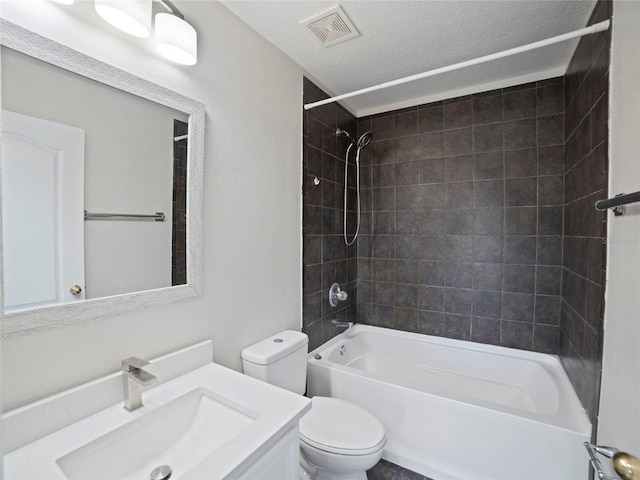 full bathroom with a textured ceiling, vanity, toilet, and tiled shower / bath combo