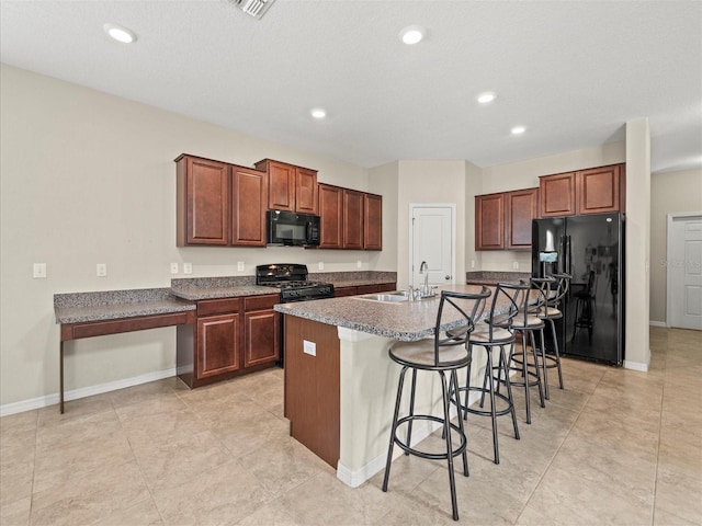 kitchen with a textured ceiling, a kitchen island with sink, a kitchen bar, black appliances, and sink