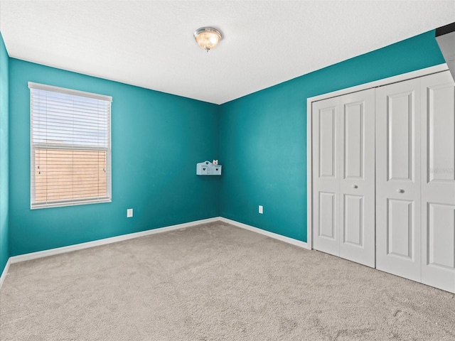 unfurnished bedroom featuring carpet, a textured ceiling, and a closet