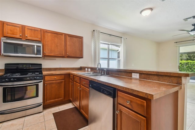 kitchen featuring ceiling fan, light tile patterned floors, sink, kitchen peninsula, and stainless steel appliances