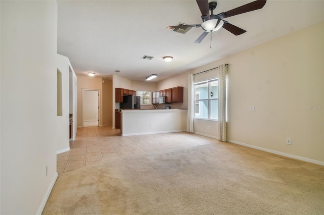 unfurnished living room featuring ceiling fan and light colored carpet