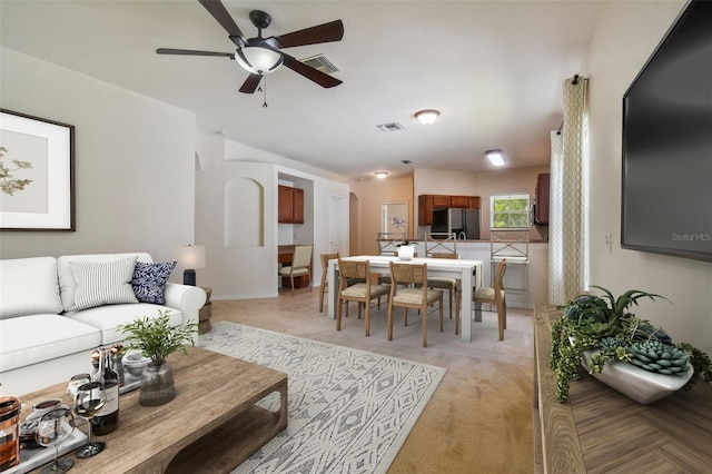 carpeted living room with ceiling fan