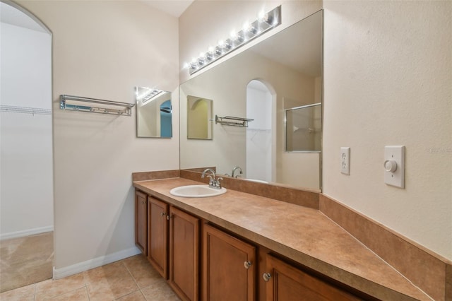 bathroom featuring tile patterned flooring, a shower with door, and vanity