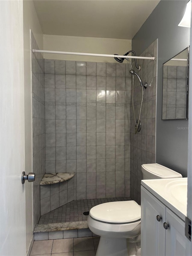 bathroom with vanity, tile patterned flooring, toilet, and tiled shower