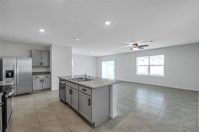 kitchen featuring appliances with stainless steel finishes, an island with sink, sink, gray cabinets, and ceiling fan