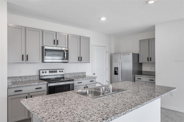 kitchen featuring a kitchen island with sink, light tile patterned floors, stainless steel appliances, and sink