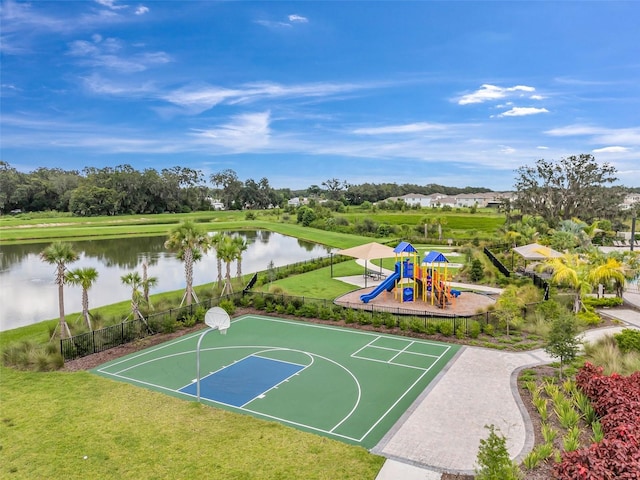 view of sport court with a water view, a lawn, and a playground