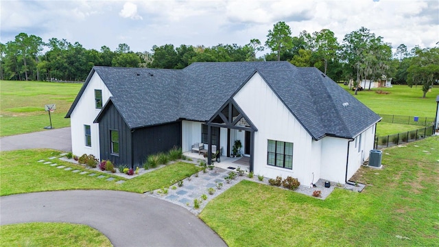 modern farmhouse style home with a front yard, central AC, and covered porch