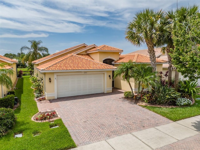 mediterranean / spanish-style house with a garage and a front lawn