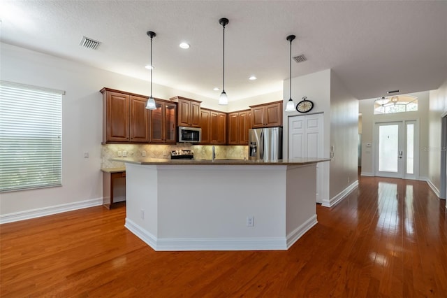 kitchen with french doors, a center island with sink, stainless steel appliances, and dark hardwood / wood-style floors