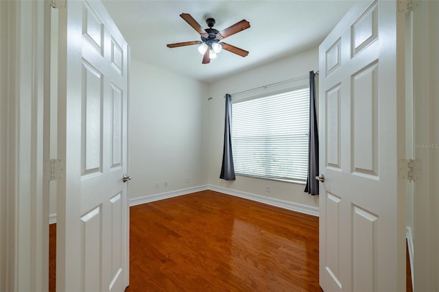 unfurnished bedroom featuring a ceiling fan, baseboards, and dark wood finished floors