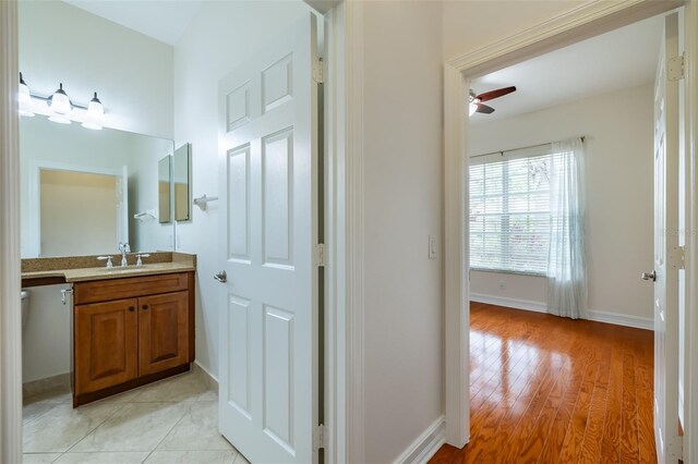 bathroom with baseboards, wood finished floors, ceiling fan, and vanity