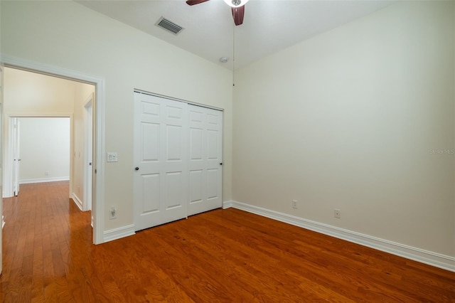 unfurnished bedroom with a closet, visible vents, baseboards, wood finished floors, and a ceiling fan