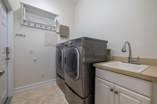 clothes washing area with washer and dryer, light tile patterned flooring, cabinets, and sink