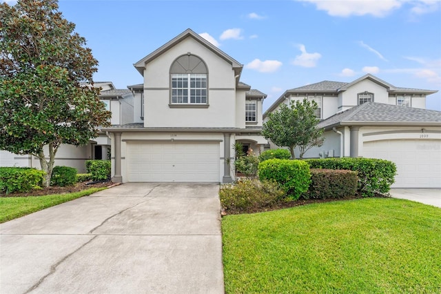 traditional home with a shingled roof, a front lawn, concrete driveway, stucco siding, and an attached garage