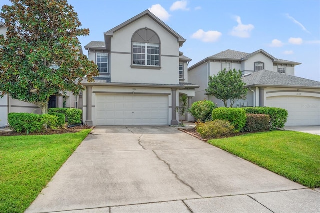 traditional-style home featuring a garage, stucco siding, driveway, and a front yard