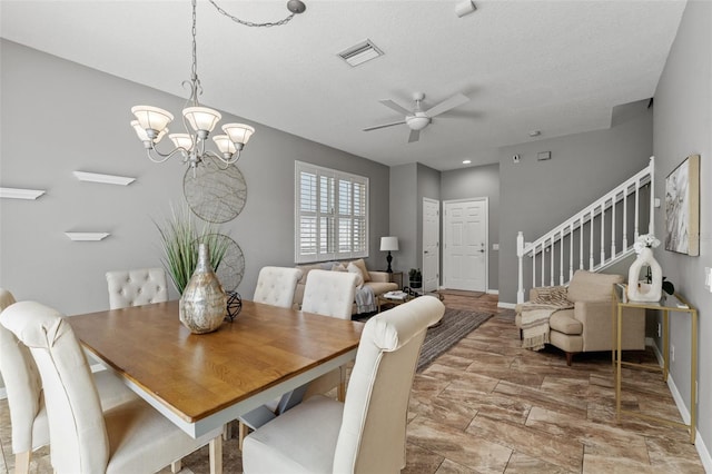 dining space featuring ceiling fan with notable chandelier and a textured ceiling