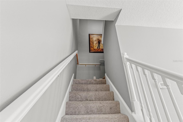 stairs featuring a textured ceiling