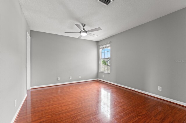 empty room with a textured ceiling, ceiling fan, and hardwood / wood-style flooring